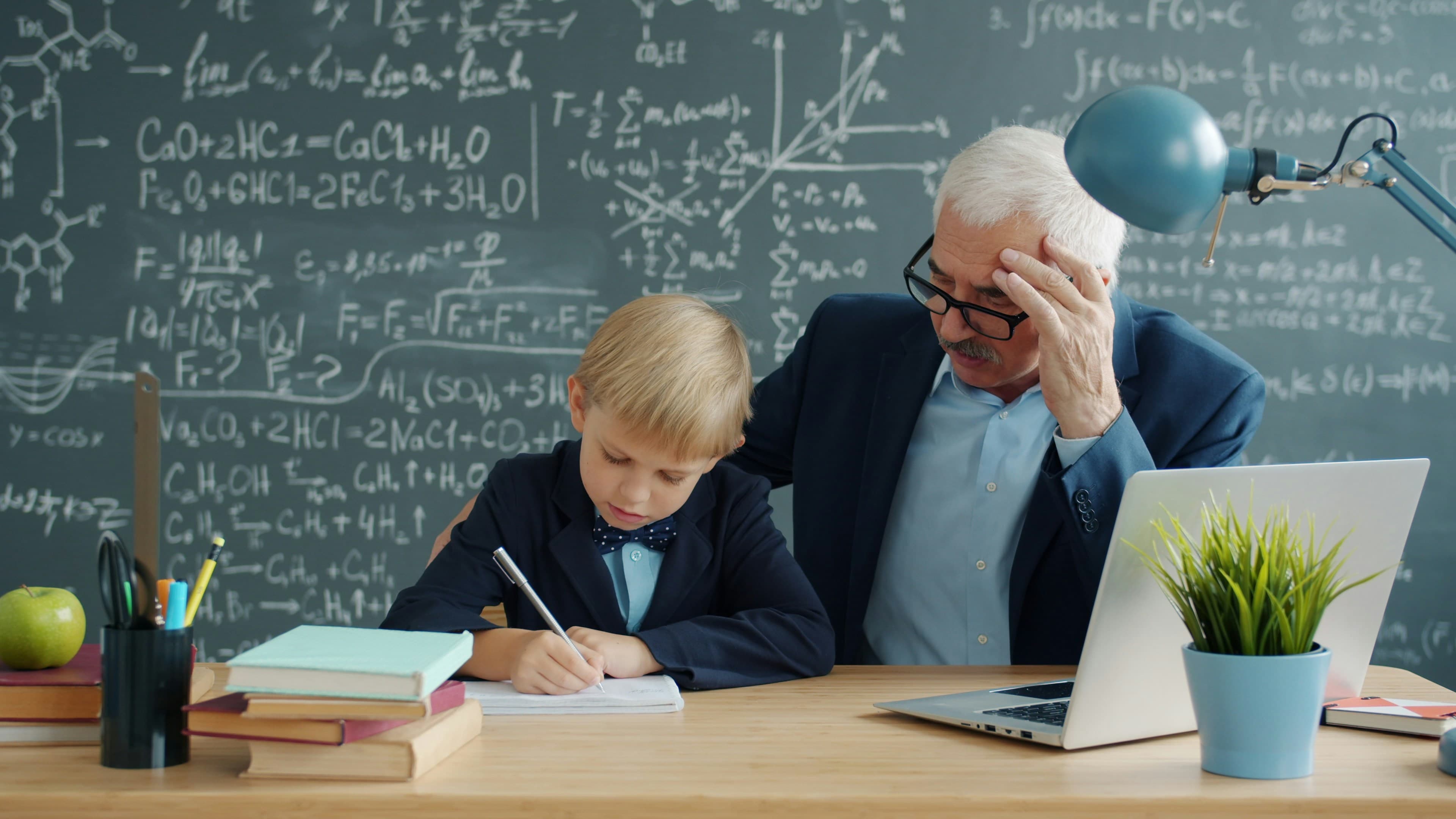 A teacher helping a young student at a desk